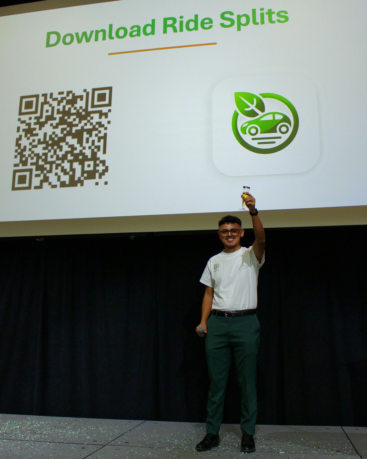 A team member on stage raising a glass in front of the Download Ride Splits screen