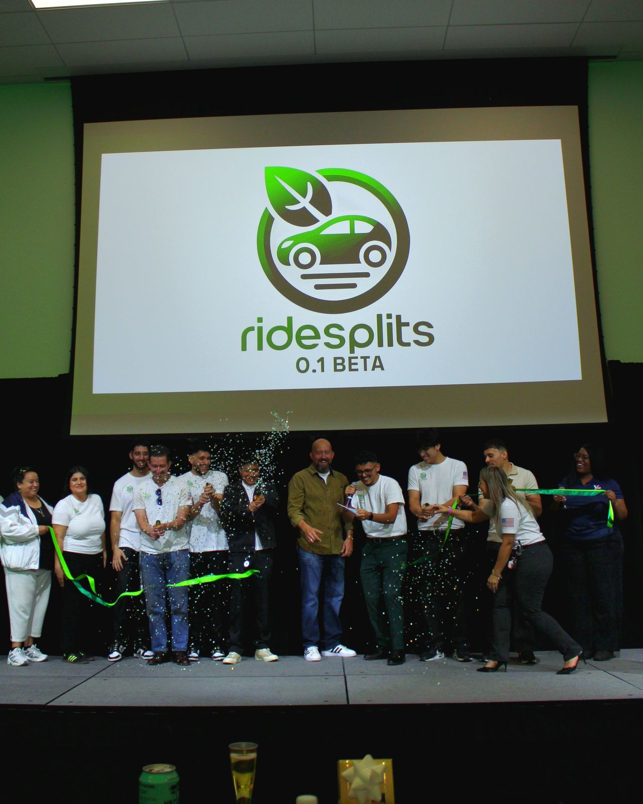 The Ride Splits team cutting a green ribbon on stage at the beta launch
