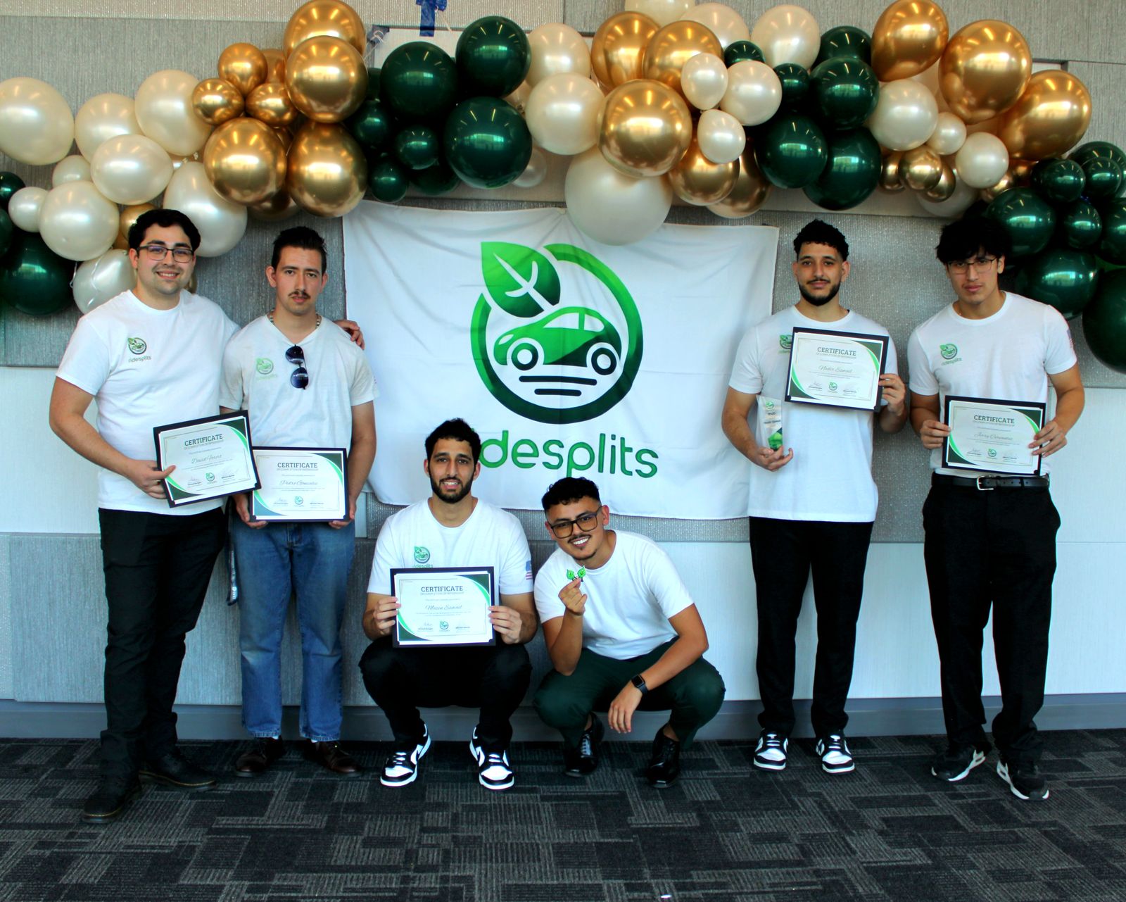 Team members holding certificates in front of a Ride Splits banner